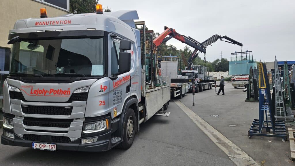 Photo de deux camions de transport de l'entreprise Lejoly-Pothen avec leur grue de manutention déployée